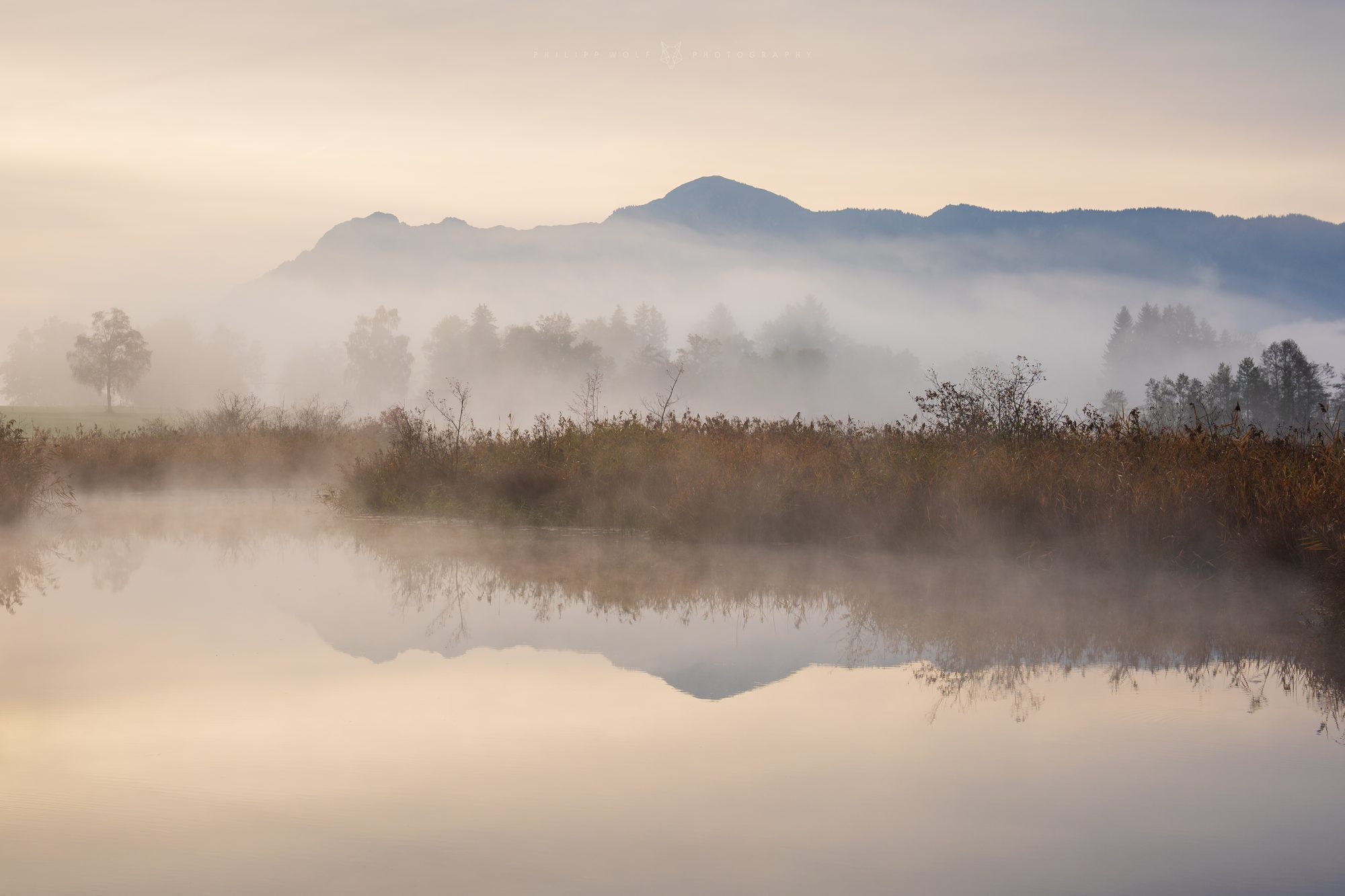 Nebliger See mit Bergsilhouette im Morgenlicht