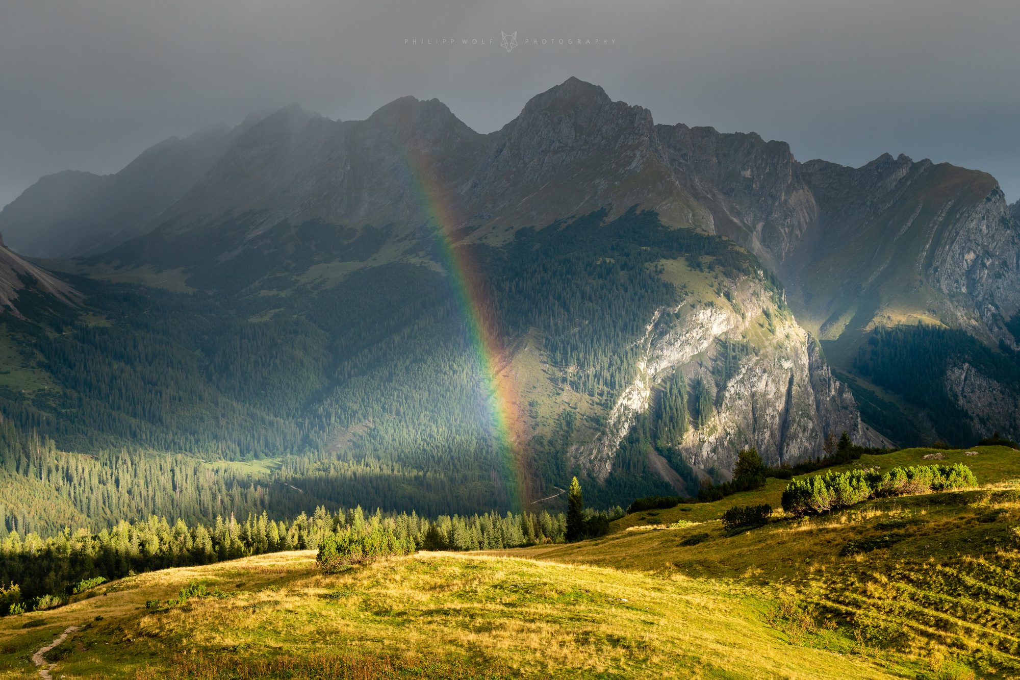Regenbogen über einer Bergwiese in den Alpen