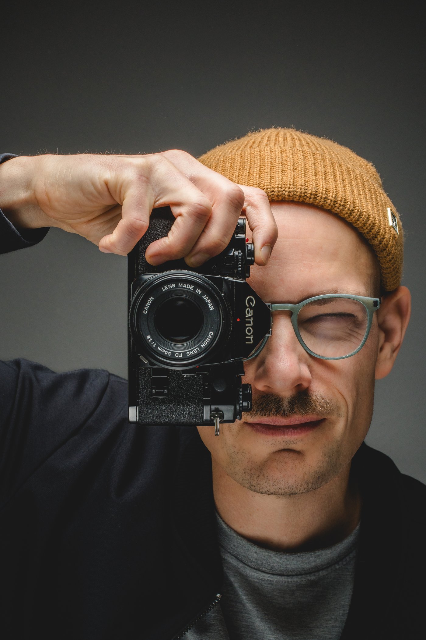 Philipp Wolf blickt durch eine analoge Canon-Kamera